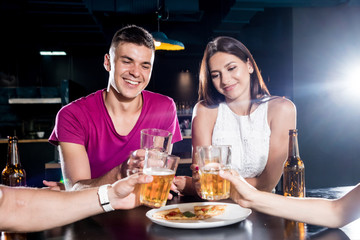 Cheerful friends in the pub. Drinking beer, talking, having fun.
