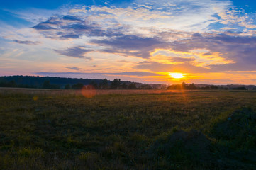 Fototapeta na wymiar Rural landscape at sunset, clouds, fields, countryside, flares, grain in front, nature