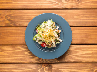 Salad chiken, tomatoes and herbs on a wood background