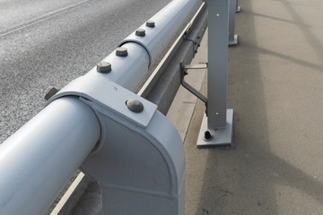 Street road fence made of pipes connected by steel bolts. Round gray pipes for pedestrian safety.