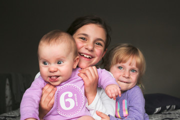 Close up Portrait of Three Beautiful Sisters, One Cute Toddler Girl , 6 Month Old Baby Girl, 7...