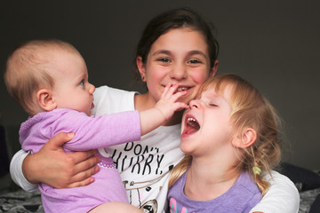 Close up Portrait of Three Beautiful Sisters, One Cute Toddler Girl , 6 Month Old Baby Girl, 7...