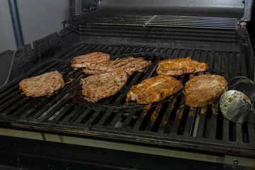 Juicy large pieces of meat are cooked on a barbecue. Marinated meat is fried on an iron gas.
