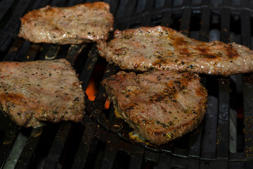 Pickled pork meat is grilled on an iron gas grill. Juicy large pieces of beef meat are cooked.