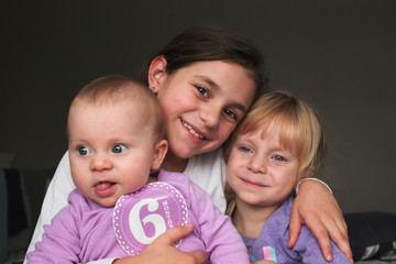 Close up Portrait of Three Beautiful Sisters, One Cute Toddler Girl , 6 Month Old Baby Girl, 7...