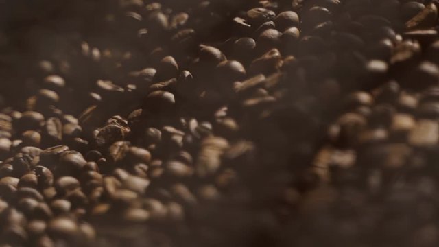 Freshly roasted coffee beans spin in a roster. Closeup of coffee beans after roasting. Slow motion