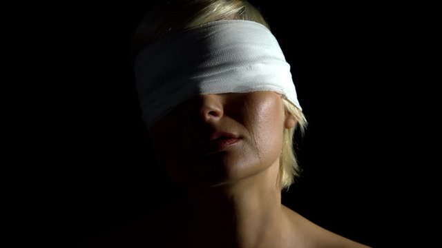 Problematic blonde hair lady covering her both eyes with white bondage on isolated dark background while tears are dripping down ideal for depression expression mock up