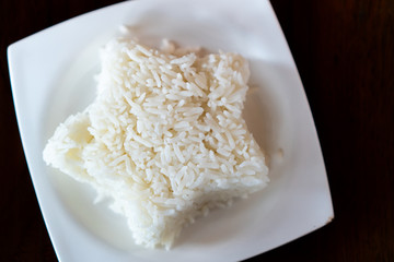 Jasmine rice was shaped in star put on a white plate placed on a dark brown wooden table.