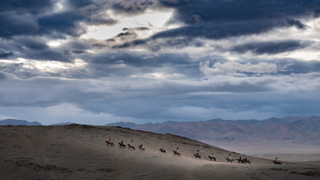 West Mongolia large panorama with dark clouds in Altai landscape with group of eagle hunters scouting