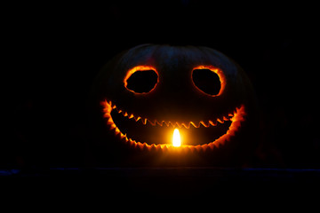 funny pumpkin head is illuminated by a candle in the dark