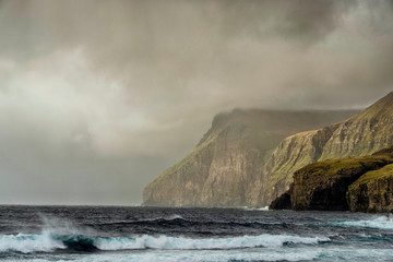 Landscape of giant sea cliffs overlooking the ocean in Faroe Islands.