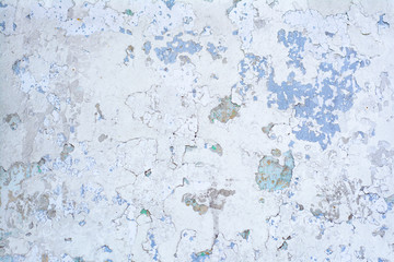 White painted concrete wall with peeling paint and green stains in the cracks