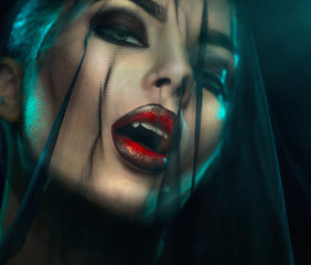 Vampire Halloween Woman portrait with black veil on a face. Beauty Sexy Vampire Girl with teeth, bloody red lips. Vampire makeup Fashion Art design. Mysterious model girl make up. Fangs. Darkness