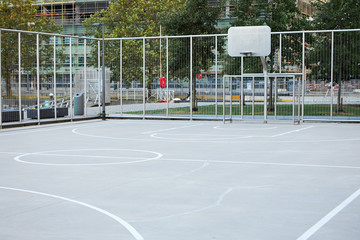 Spacious outdoor basketball court with rim and concrete flooring with white marking. Street ball...
