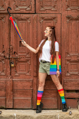 Bisexual girl in colorful clothes posing over old door on background.