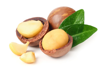 Macadamia nut with pieces and green leaves isolated on a white background