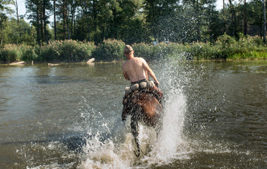 The rider on a horse crosses the shallow lake