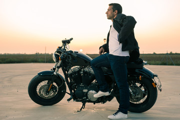 Fototapeta na wymiar Biker man with his custom motorcycle at sunset.