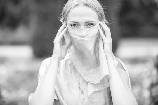 Black and white portrait of young girl covering her face with veil outdoor