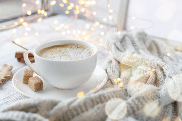 Cup of coffee, brown sugar, knitted scarf, garland. Autumn mood. Cozy autumn composition. Hygge concept. Soft focus