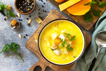 The concept of healthy and diet food. Autumn pumpkin and turkey soup with cream on a light stone or slate table. Top view flat lay.
