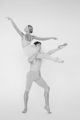 Fototapeta na wymiar Young couple of modern ballet dancers posing over white studio background