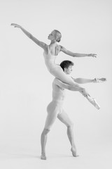 Young couple of modern ballet dancers posing over white studio background