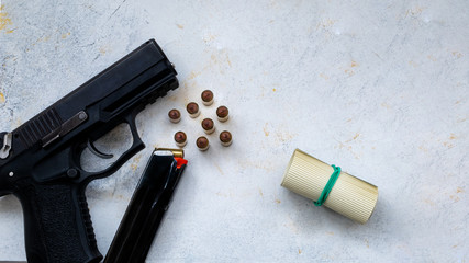 9 mm pistol gun bullets strewn and roll american dollar banknotes on rustic oak table.