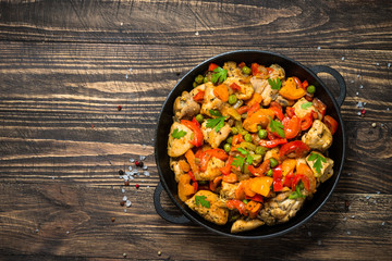 Chicken Stir fry with vegetables on wooden table.
