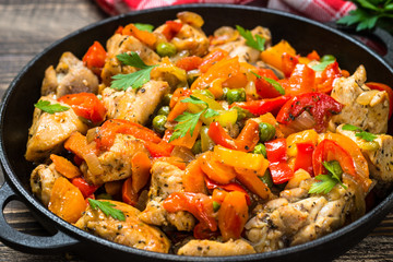 Chicken Stir fry with vegetables on wooden table.