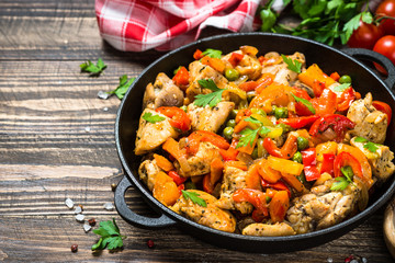 Chicken Stir fry with vegetables on wooden table.