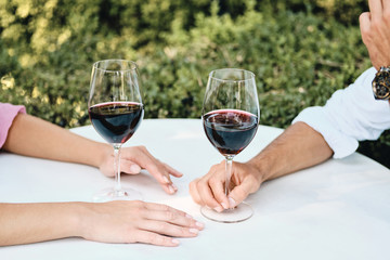 Close up couple with glasses of red wine on date in restaurant outdoor