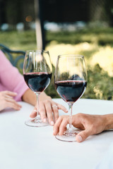 Close up photo of couple with glasses of red wine on date in restaurant outdoor