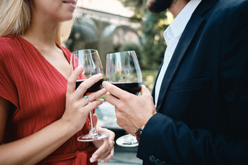 Close up young attractive couple with glasses of wine celebrating engagement together in restaurant outdoor