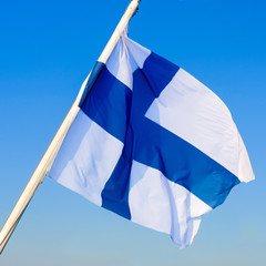 National flag of Finland fluttering on the wind against clear blue sky. Finnish flag on flagpole,
