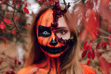 Young blonde girl with halloween face art posing outdoor.  Helloween celebration concept.