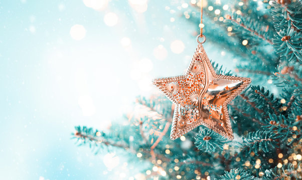 Christmas fir tree branches with golden star decoration  on blurred blue background. Christmas and Winter concept.