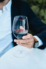 Close up male hand holding glass of wine in restaurant outdoor