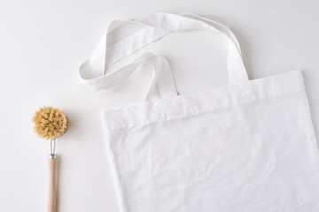 shopping bag with copy space and wooden brush on a white background, top view. Zero waste concept