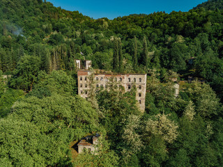 Fototapeta na wymiar Ruined overgrown school in ghost mining town Akarmara, consequences of war in Abkhazia, aerial view from drone