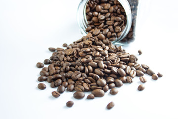 Coffee beans spilling out of the jar, white background