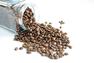 Coffee beans spilling out of the jar, white background
