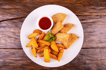 Nuggets from fish breaded with tomato sauce and rural potato