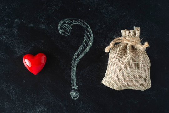 Love or money choise. red heart and a bag with money. Chackboard wih question mark. Making right decision.