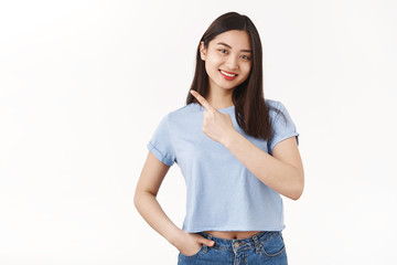 Good-looking friendly outgoing asian brunette female pointing upper left corner assertive smiling broadly give advice what choose grin delighted discuss cool promo standing white background