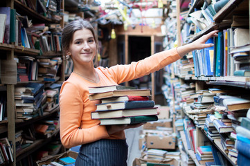 girl student is looking for literature in the old library, she takes a book from the bookshelf, a...