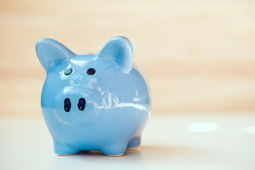 Close up of blue piggy bank standing on wooden background with copy space.