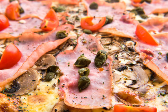 Macro photo of tomato, ham, anchovy and cheese on pizza