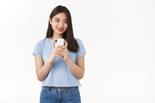 Lucky cute tender asian brunette girl internet social media blogger record video hold smartphone look camera taking selfie mirror shooting friend making photograph stand white background