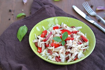 Salad of white cabbage, boiled chicken, red sweet pepper and brown beans in a green bowl on a brown concrete background. Healthy food.